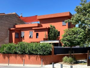 An orange building with trees and bushes in front of it