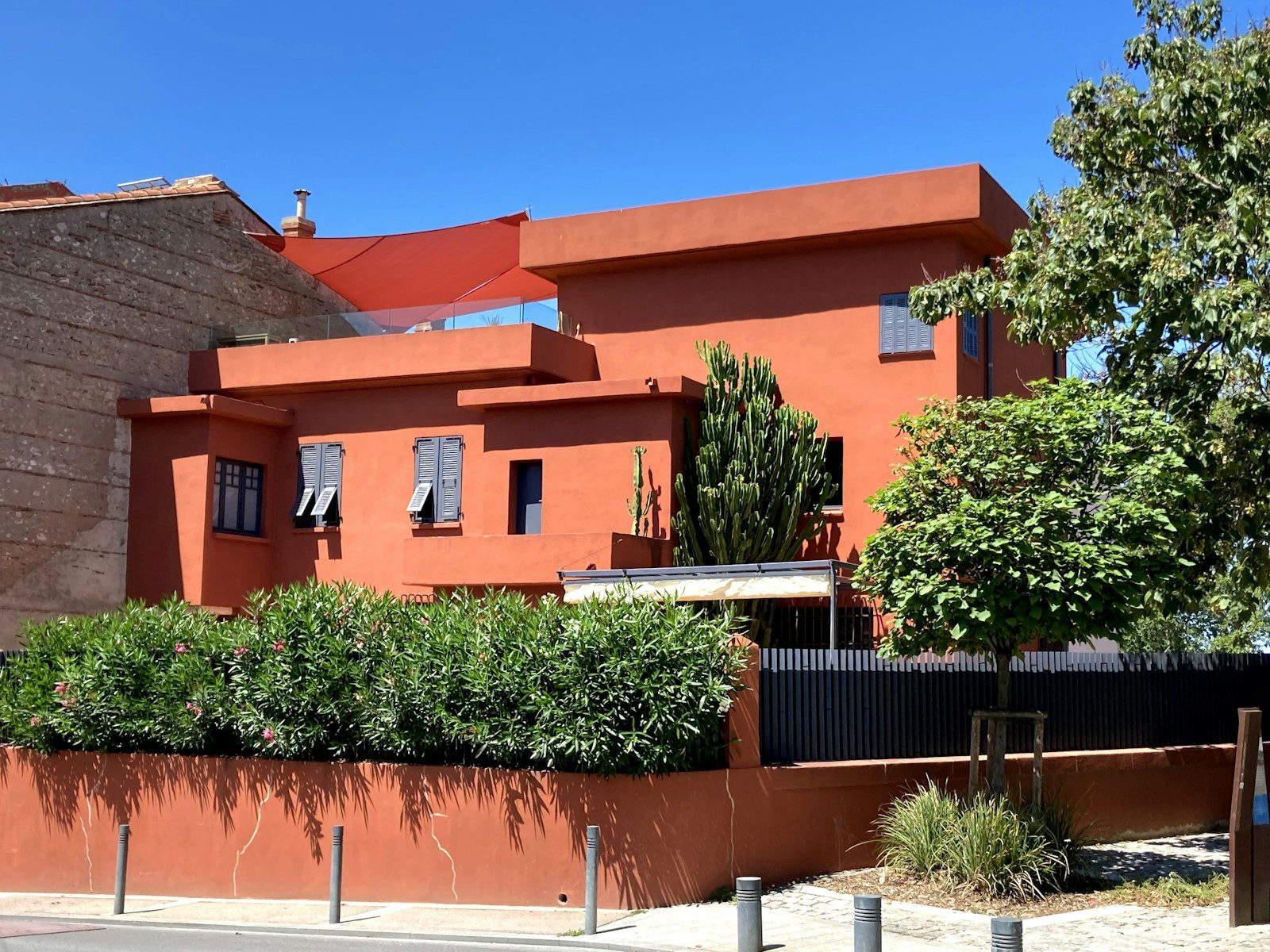An orange building with trees and bushes in front of it