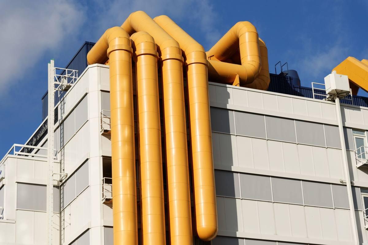 Des tuyaux jaunes massifs s'élèvent du toit d'un bâtiment blanc