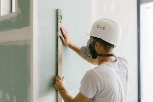 Un ouvrier en sécurité mesure verticalement un panneau de plâtre