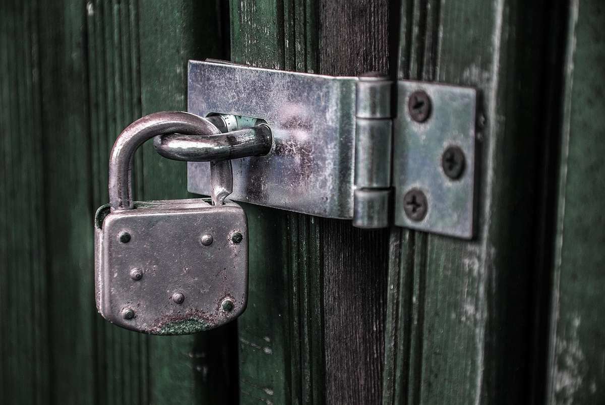 Un cadenas métallique verrouille une poignée sur une porte verte Un cadenas métallique verrouille une poignée sur une porte verte