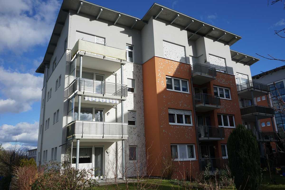 Immeuble moderne à façade blanche et orange sous ciel nuageux