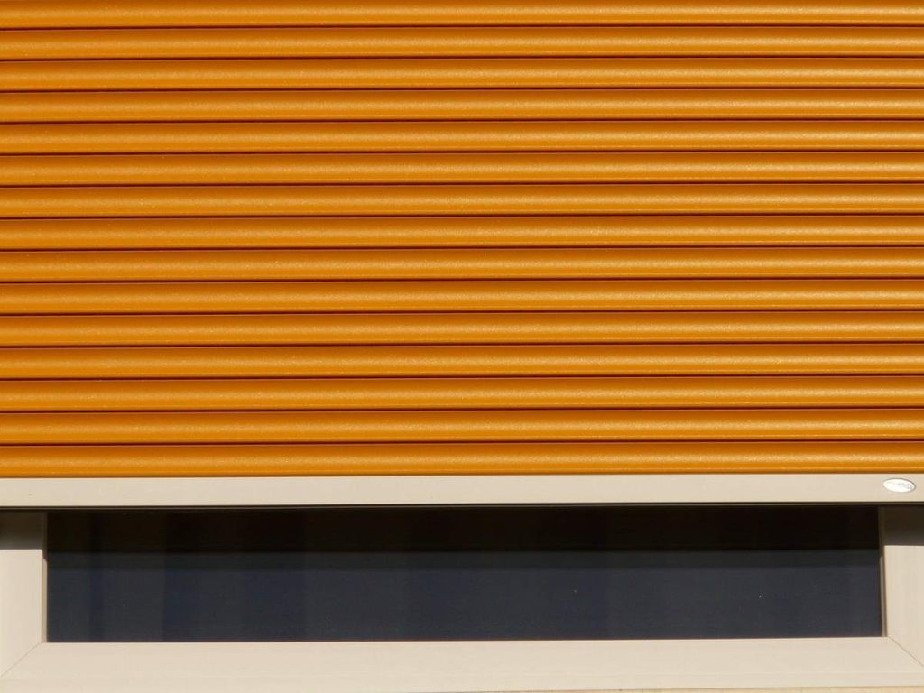 Volet roulant orange partiellement déroulé sur une fenêtre