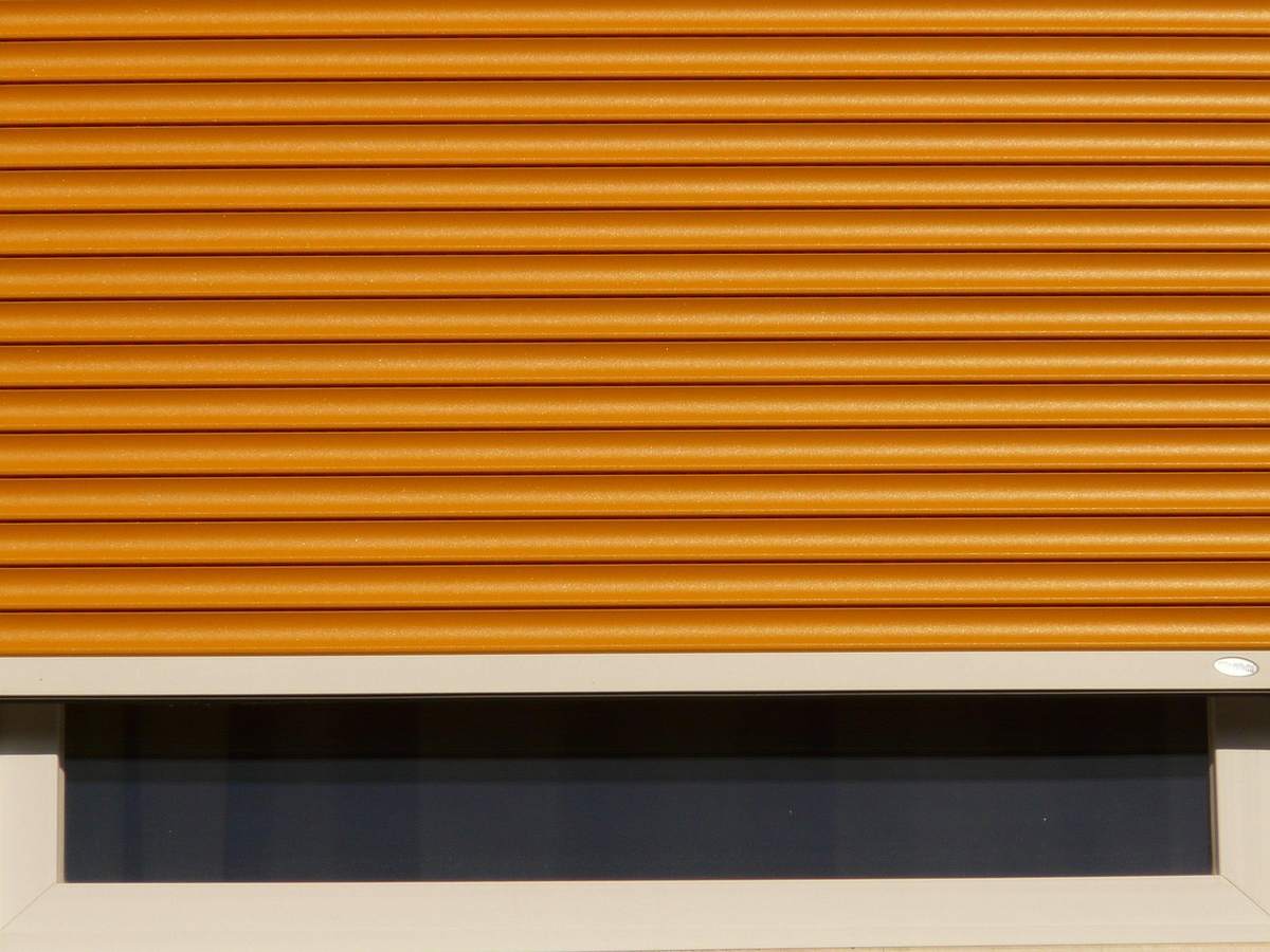 Volet roulant orange partiellement déroulé sur une fenêtre